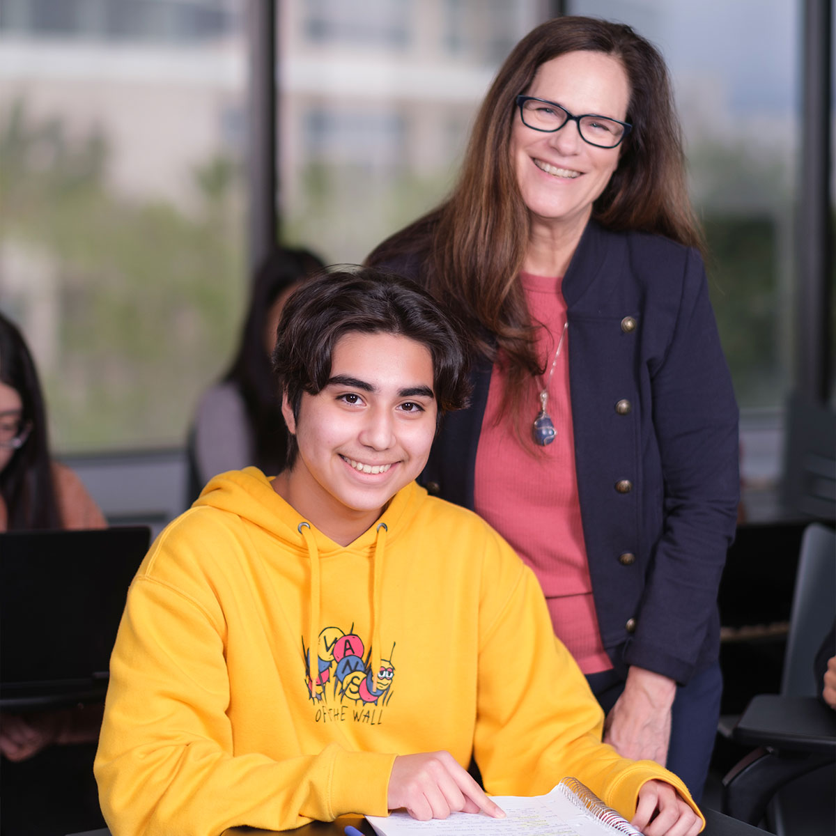 Student in yellow hoodie smiling with teacher